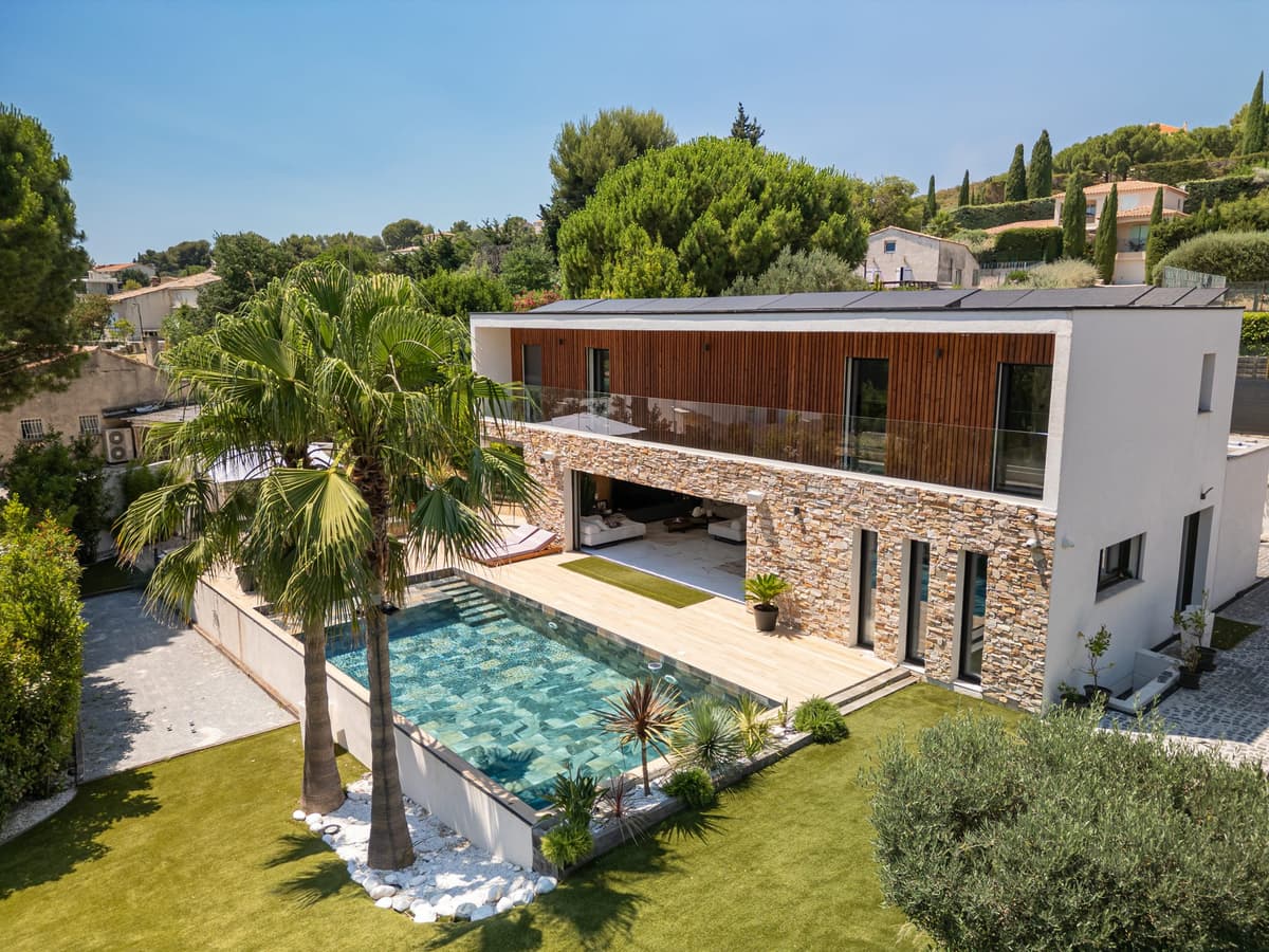 Villa contemporaine bois et pierre, piscine et palmiers vus du ciel